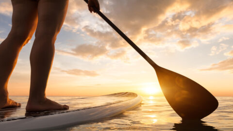 A tourist paddle boarding in Maui at sunset