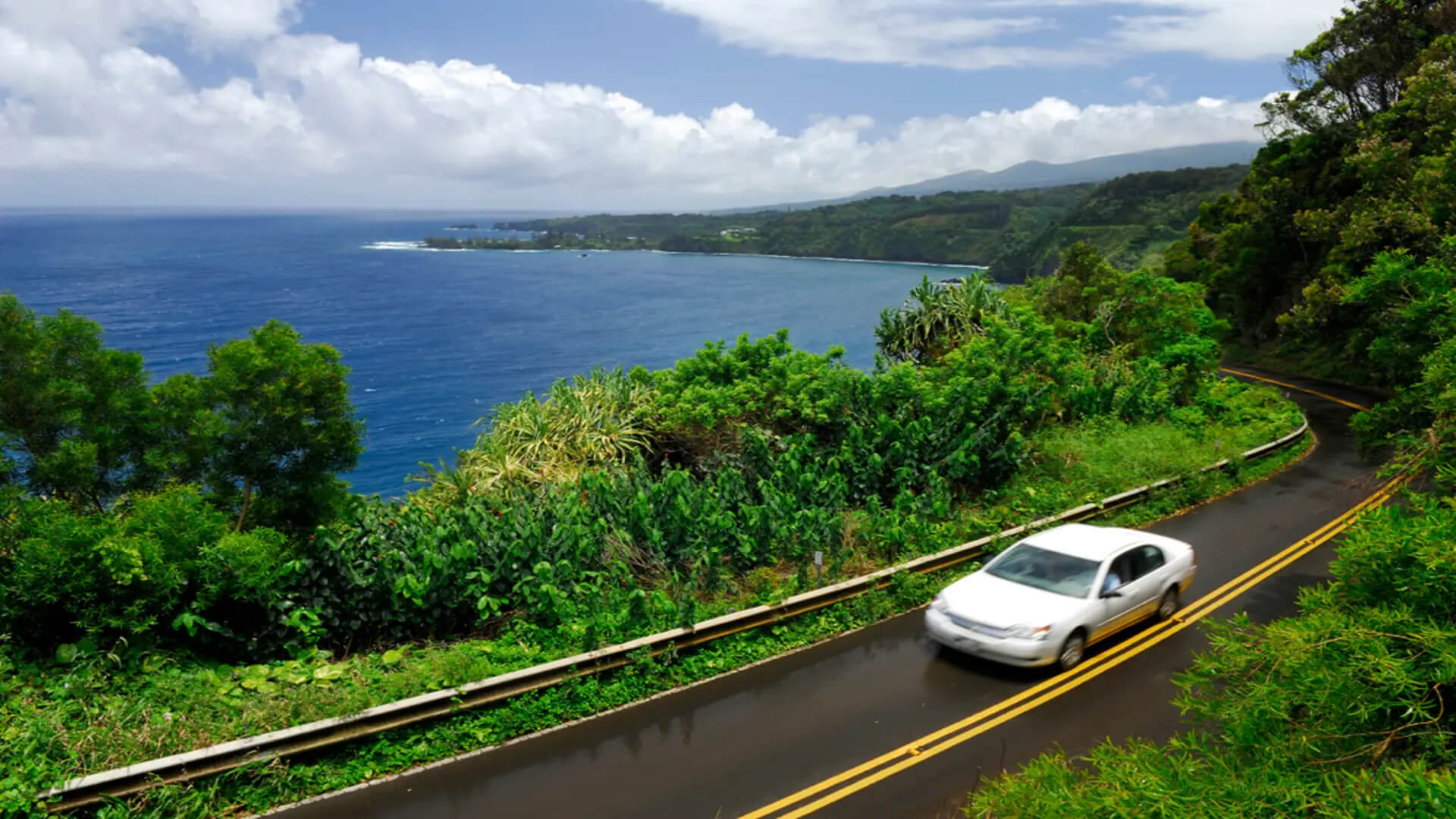 A rented car driving along a scenic road next to the ocean in Maui
