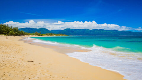 A view of the beach with turquoise waters and mountains in the background at H.A. Baldwin Beach Park