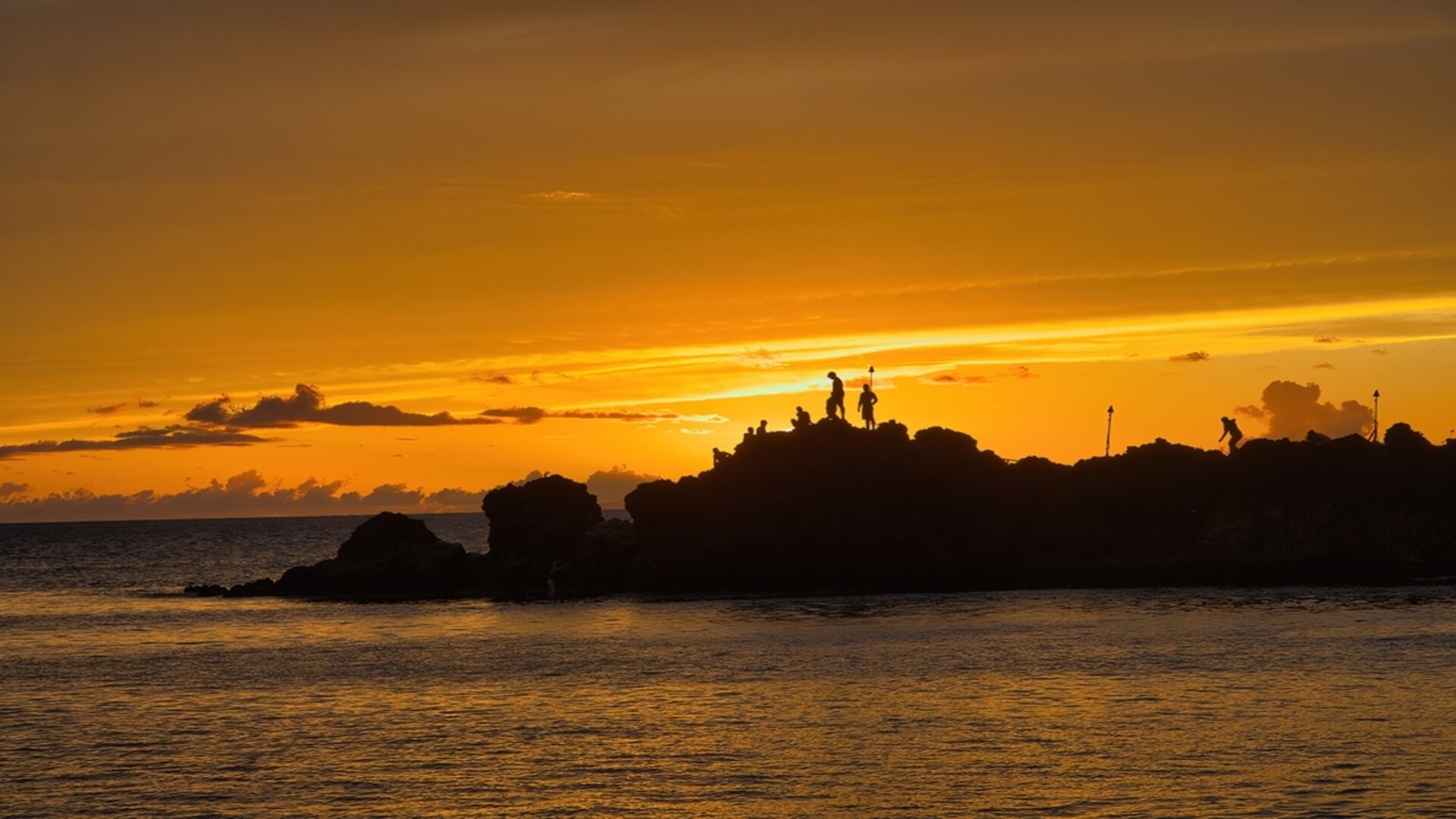 Cliff jumpers on Black Rock at sunset in Maui