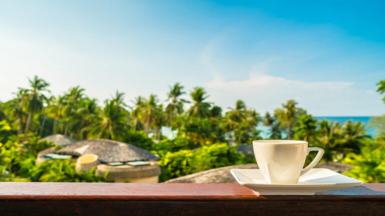 A cup of coffee on a lanai overlooking palm trees at a resort in Maui